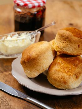 Photo of delicious scones on a plate with clotted cream and jam.