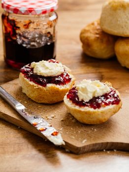 Photo of delicious scones on a plate with clotted cream and jam.
