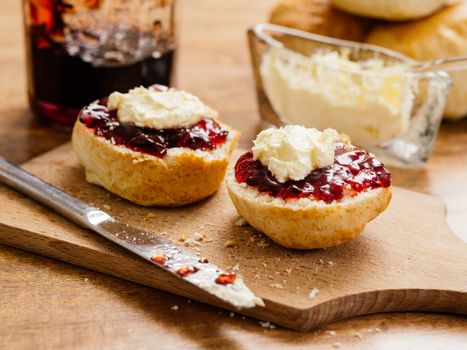 Photo of delicious scones on a plate with clotted cream and jam.