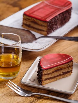 Photo of a slice of Scottish whisky cake and a dram of whisky on top of a wood table.