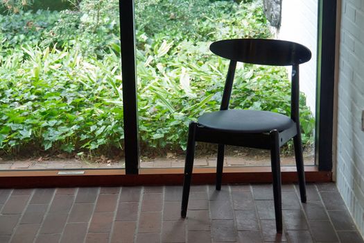 Classic design black wooden chair by a glass window                               