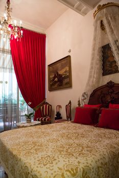 Classical and traditional luxury Spainish hotel room in Barcelona with red curtains and pillows.