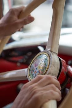 Close up of hands of a man holding the steering wheel of a vintage car while driving in Barcelona.