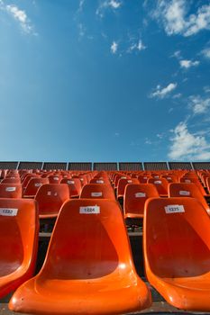 Lots of orange seats at an outdoor venue with a blue sky