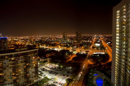 Aerial view of Miami Beach at night from a tall building with view on the swimming pool, the streets and the surrounding.