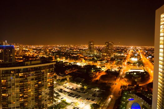 Aerial view of Miami Beach at night from a tall building with view on the swimming pool, the streets and the surrounding.