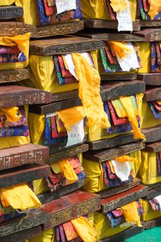 Old wood boxes containing precious Tibetan old and sacred text. Each boxe is covered by the yellow, red and blue fabrics. Holy colors in Tibet.