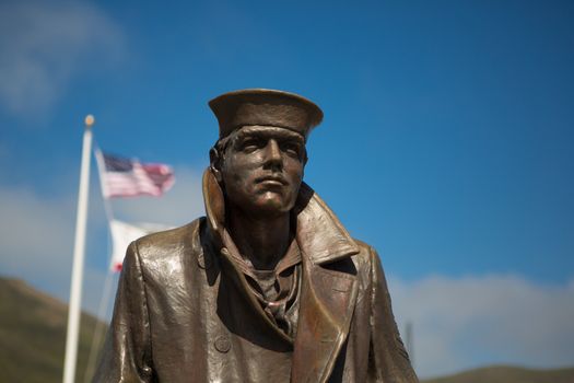 Statue the Sailor and the flags of the United States at the Golden Gate Bridge lookout area within the San Francisco Bay. United States 2012.