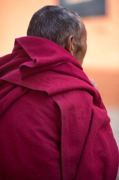 Back of the old Buddhist monk dressed in red in Tibet, China