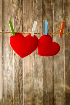 Cute big red heart hanging on the clothesline. On old wood background.