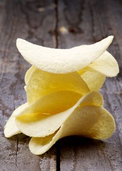 Stack of Crunchy Potato Chips closeup on Rustic Wooden background