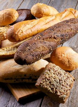 Heap of Various Various Buns, Baguette, Poppy Seed and Sesame Buns, Rye and Whole Wheat Bread closeup on Rustic Wooden background