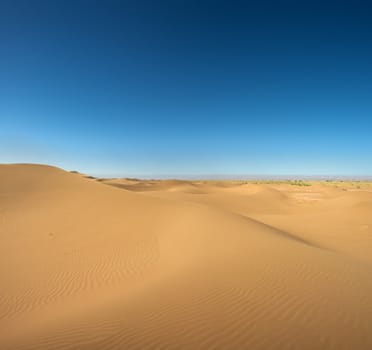 Sahara desert close to Merzouga in Morocco with blue sky and clouds.