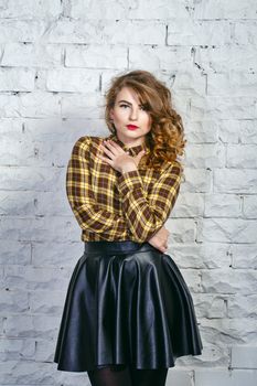 Attractive young girl in plaid shirt and leather skirt