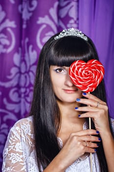 Attractive young brunette girl hiding behind big lollipop