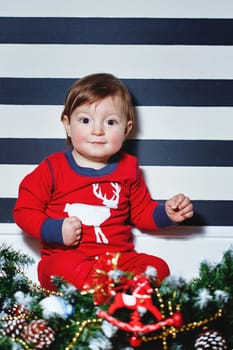 Little boy sitting on the floor surrounded by Christmas decorations