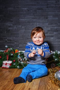 Little boy sitting on the floor surrounded by Christmas decorations