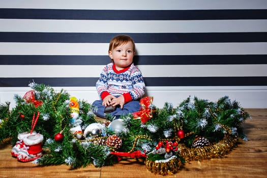 Little boy sitting on the floor surrounded by Christmas decorations