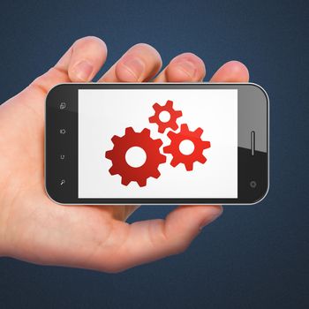 Web development concept: hand holding smartphone with Gears on display. Mobile smart phone on Blue background, 3d render