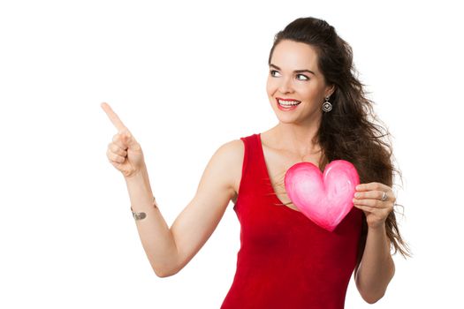 Happy smiling woman holding a love heart and pointing up to copy-space. Isolated on white.