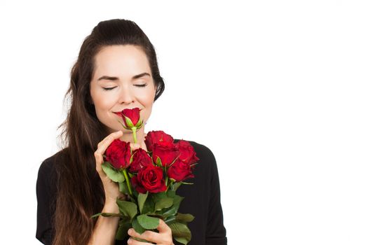 A beautiful woman dressed in black smelling red roses. Isolated on White