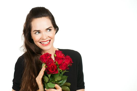 A smiling beautiful woman holding a bunch of roses and looking at copy-space. Isolated on white.