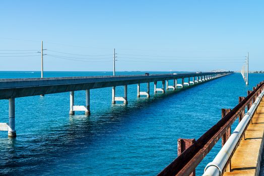 The historic Seven Mile bridge was built by Henry Flagler as part of the Overseas Railroad to Key West. The new seven mile bridge can be seen on the left running alongside the old bridge. 