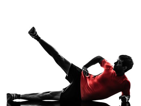 one man exercising fitness workout legs in the air lying on side in silhouette on white background