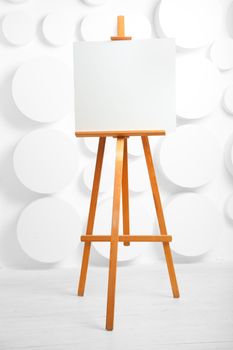 wooden easel with blank canvas in the studio