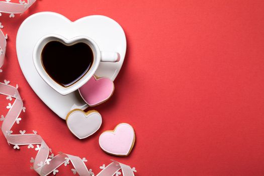 Coffee with cookie in shape of heart on red background. Composition for Valentines Day. Top view. Copy space