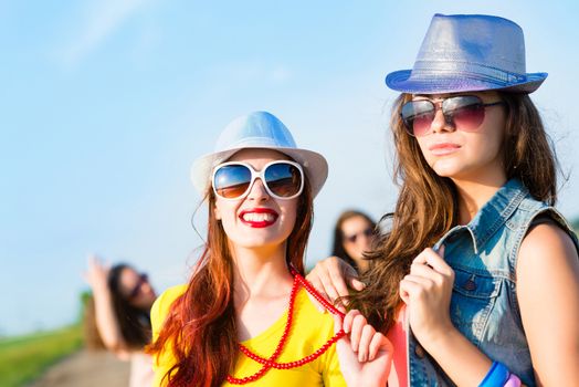 Two young girlfriends having fun on the background of blue sky and friends