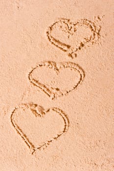 three hearts drawn on wet sand