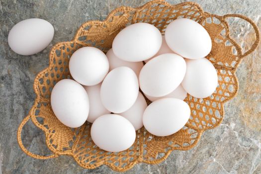 Overhead closeup view of a decorative woven wicker Easter basket filled with traditional fresh white Easter Eggs