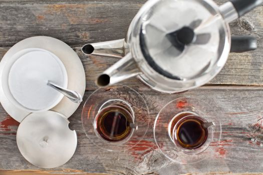 View from above showing the preparation of two hot glasses of Turkish tea using the traditional stacked kettles on an old rustic wooden table top