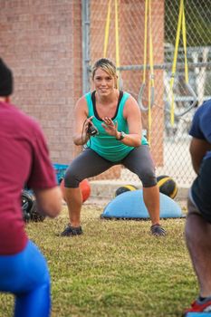 Smiling fitness trainer working with students at boot camp