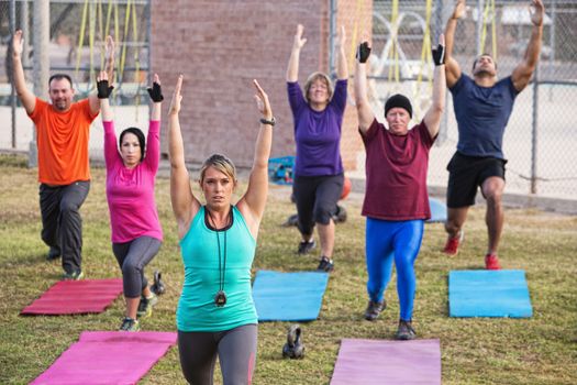 Mature adult boot camp fitness class stretching outdoors