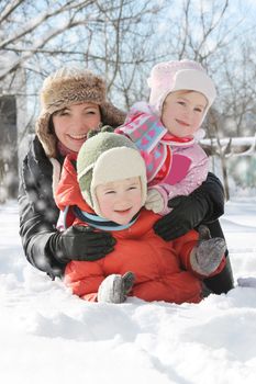 Happy mother with two children lying in snow