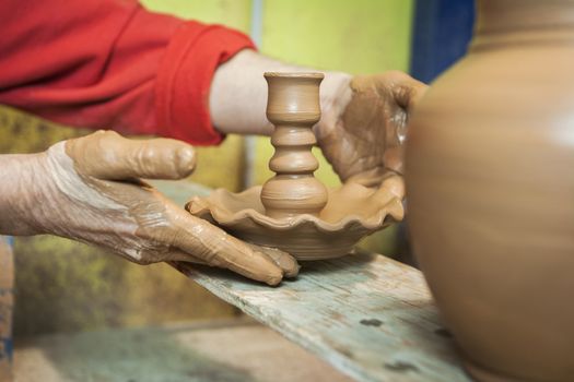 Potter by placing on a table of wood own candle holder of freshly made ceramic, clay pottery ceramics typical of Bailen, Jaen province, Andalucia, Spain