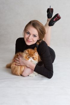 The young nice girl holds a red Persian cat on hands