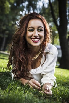 Portrait of young cheerful girl lying on the grass