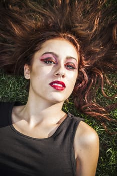 Portrait of young cheerful girl lying on the grass