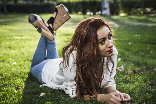 Portrait of young cheerful girl lying on the grass