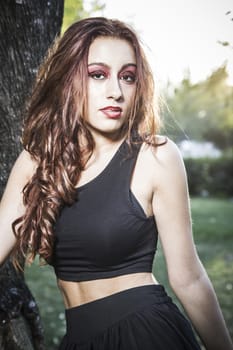 Portrait of young attractive smiling woman wearing black t-shirt at summer green park.