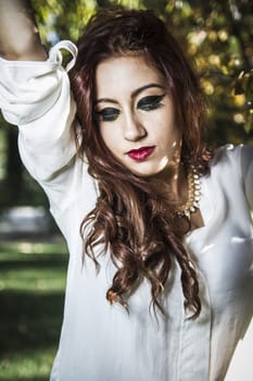 Portrait of young attractive smiling woman wearing white t-shirt at summer green park.