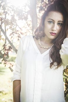 Portrait of young attractive smiling woman wearing white t-shirt at summer green park.