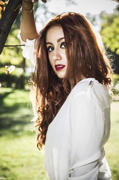 Portrait of pensive beautiful young woman, against background of summer green park.