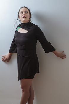 mid-thirties woman against a wall trying to hide from something and looking up