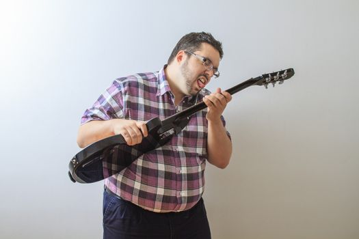 Overweight man about to lick the string of a guitar