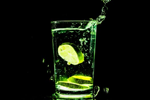A glass of cold water with slices of lemon making a splash