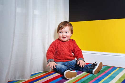 Cute little boy sitting on the floor in the living room